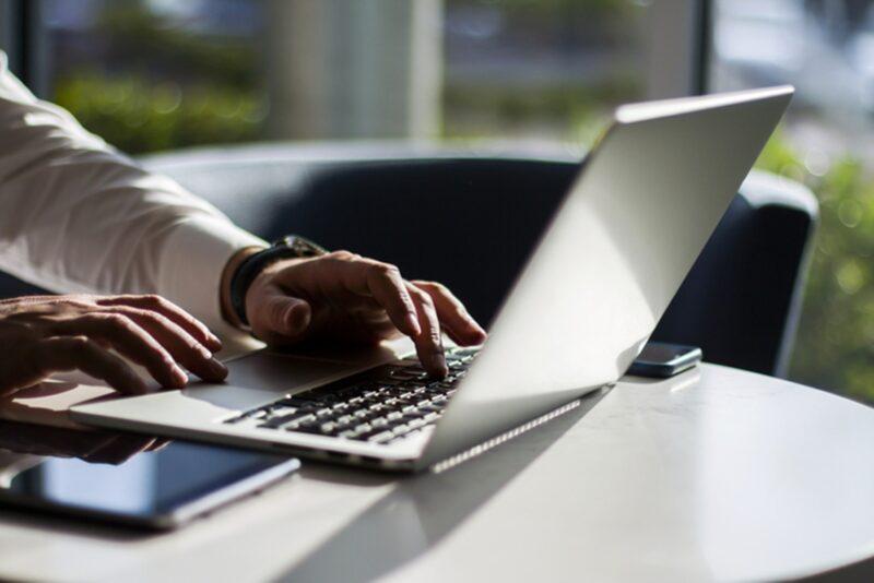 Man Working With Laptop Keyboard And Digital Tablet In Sunny Office, Business And Technology Concept. Close Up